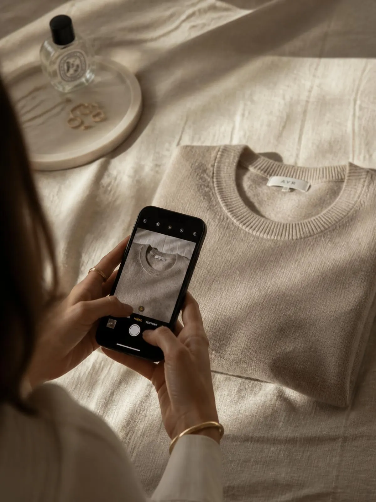 Folded neutral garments on a warm bone backdrop